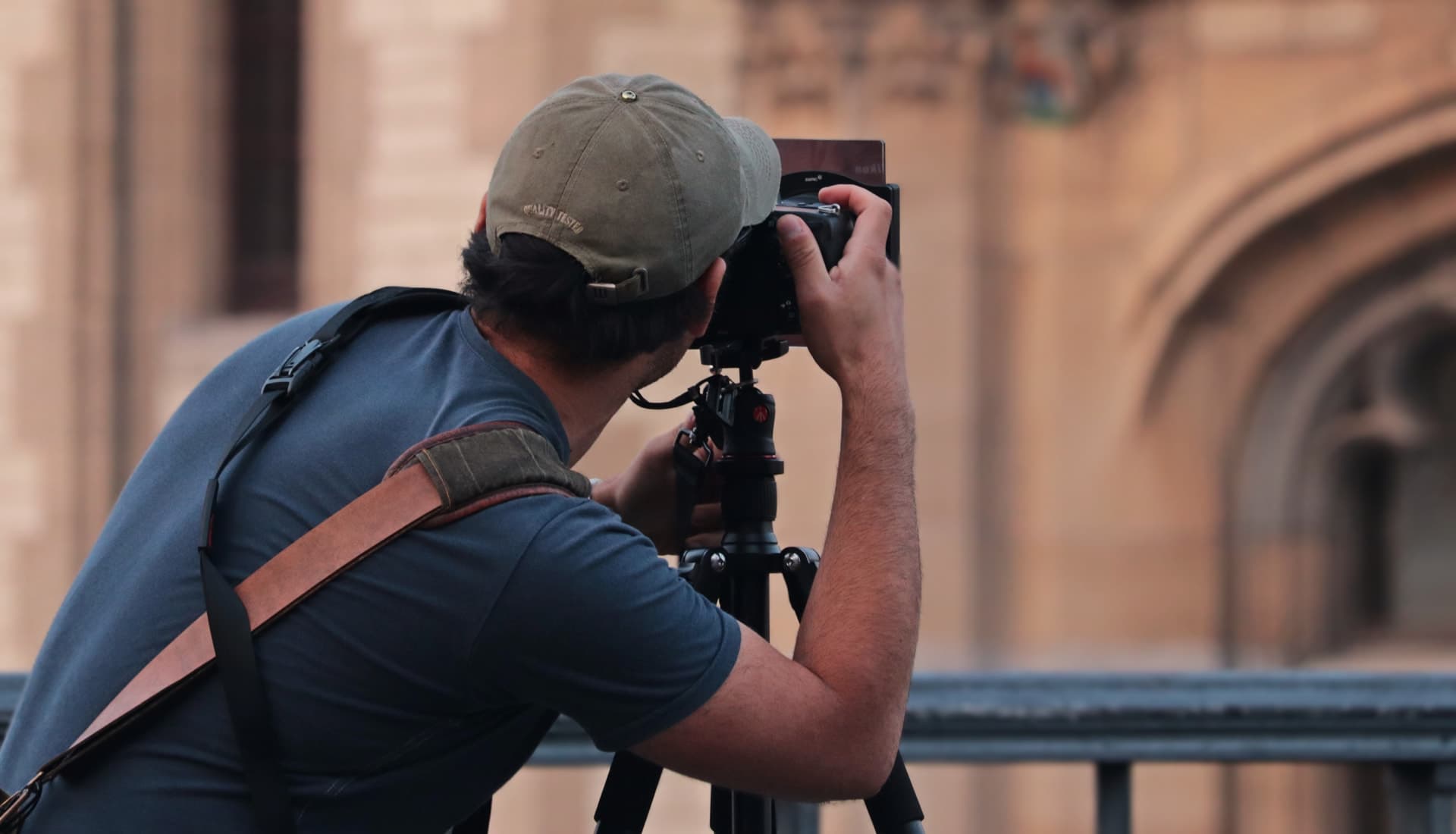 Photographe professionnel réglant son appareil sur trépied lors d'un reportage.